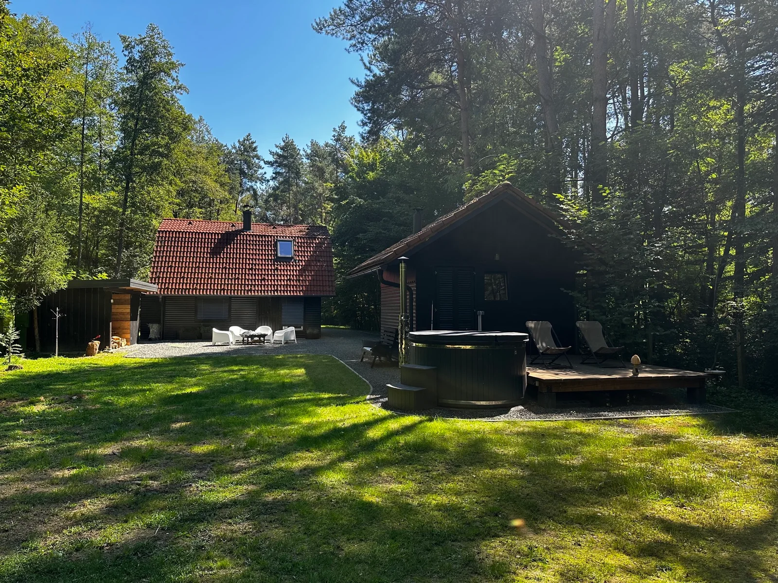 The cabin and private outdoor hot tub in a sunny woodland clearing
